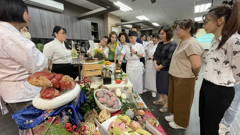 中華醫大烘焙技能訓練班學員向校長李碧娥等人介紹成果展各種烘焙作品。(圖/中華醫大提供)