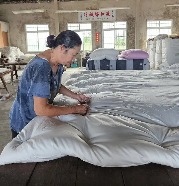 老師傅揮汗工作,將內胎被套與棉花縫合固定,全憑經驗,無需丈量。(圖/臺南市政府觀旅局 提供)