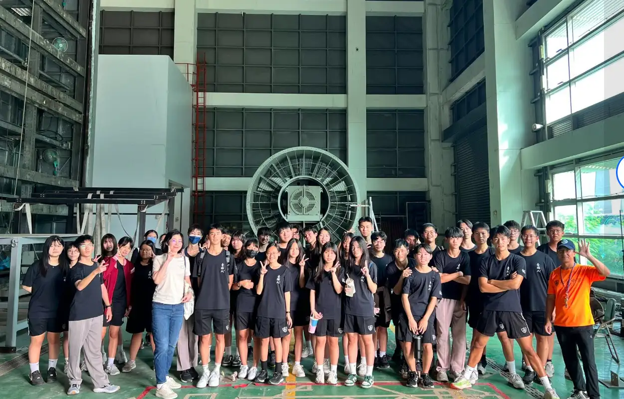 黃怡倩老師與長榮中學高二數理實驗班同學於國家地震工程研究中心「風洞實驗室」與大風扇合影。(圖/長榮中學 提供)
